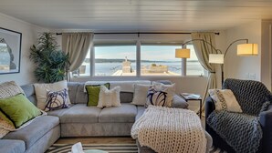 A living room with a sofa, armchairs, a large window with a view of a tower, and a lamp. - Waterfront Cabin w/ Stunning Sound Views (University Place)