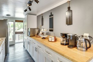 A modern kitchen with a wooden countertop, stainless steel appliances, and a view to the outdoors.