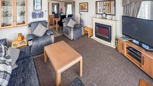 Ein Wohnzimmer mit einer Couch, einem Couchtisch, einem Kamin, einem Fernseher und einem Essbereich.