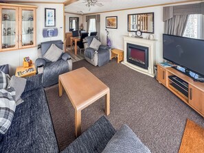 Ein Wohnzimmer mit einer Couch, einem Couchtisch, einem Kamin, einem Fernseher und einem Essbereich.
