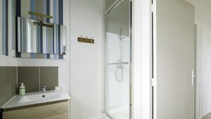 Un bagno con lavandino bianco, specchio e doccia.