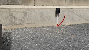 A concrete wall with a black electrical box and a red cable.