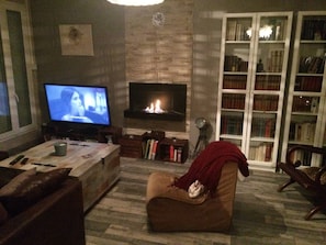 Ein Wohnzimmer mit Kamin, Fernseher, Bücherregal und Sofa.