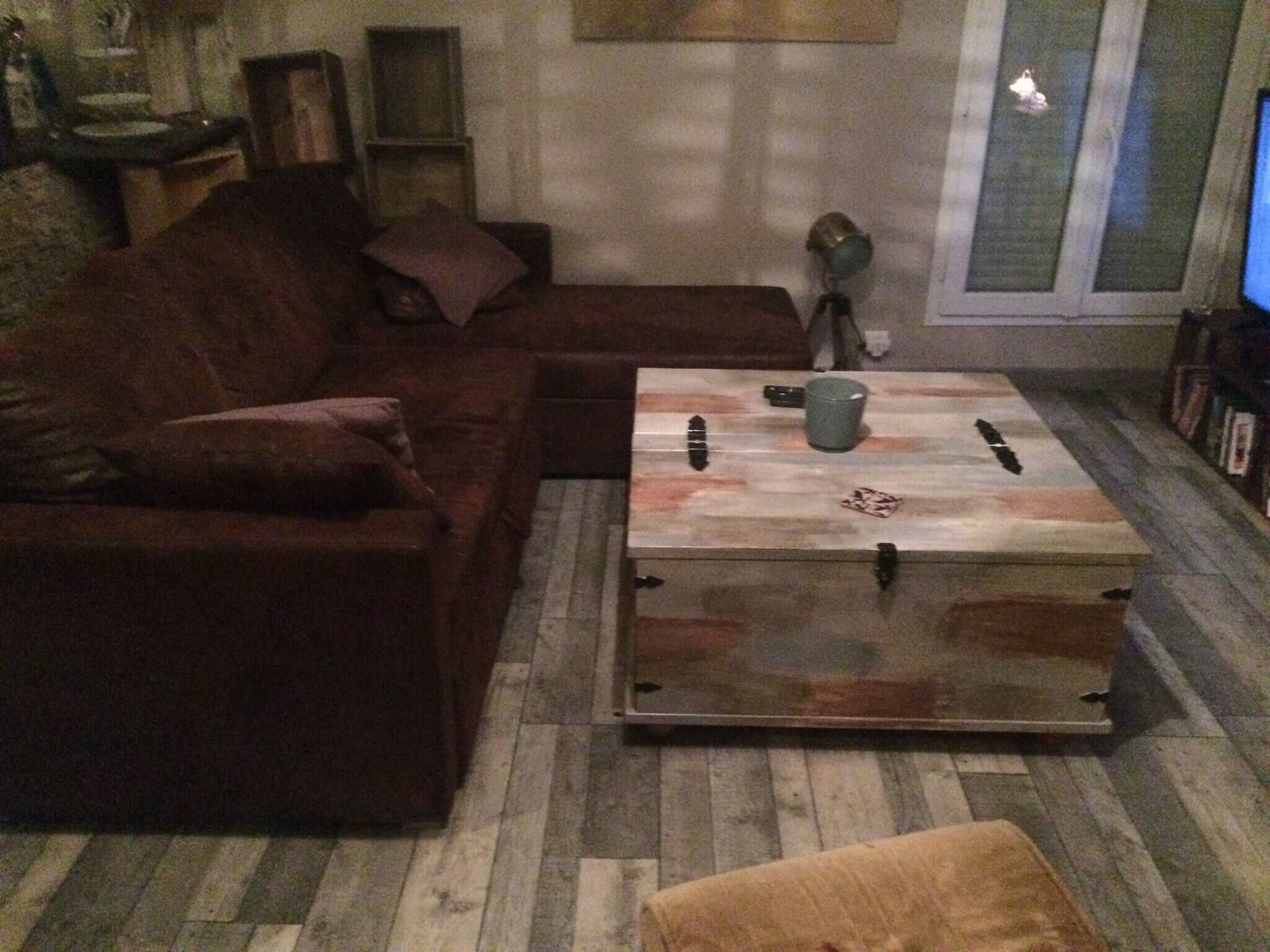 Olohuoneessa on ruskea sohva, laatikolla varustettu sohvapöytä ja oikealla puolella televisio.