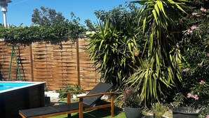 Um quintal com piscina, cadeiras de descanso e diversos vasos de plantas.