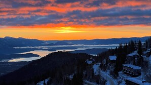 A mountain landscape with a sunset, snow-covered houses, and a lake. - Ski-in Ski-out, hot tub, on the ski run, next to the chairlift. Epic views! #2 (Sandpoint)