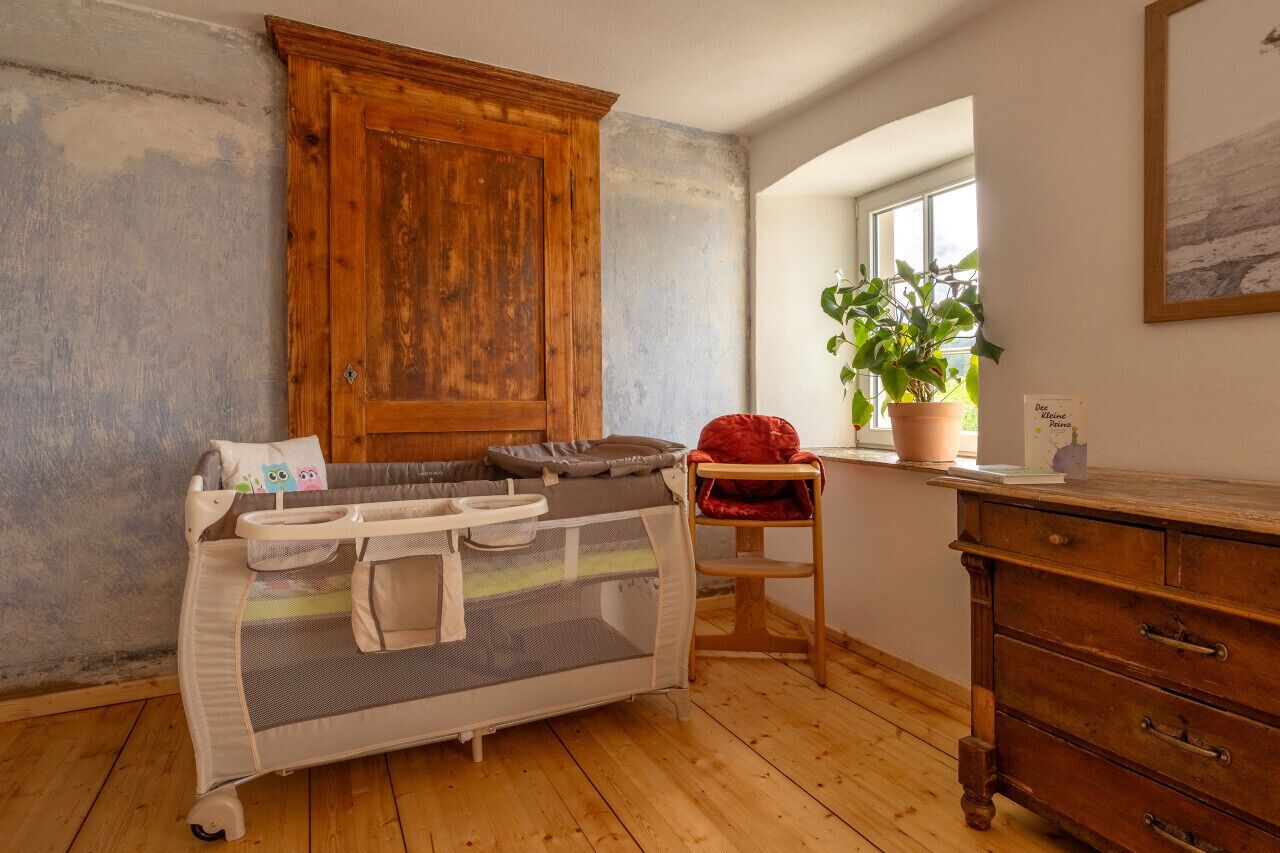 Quarto com armário de madeira, cama com dossel, planta em vaso e uma janela.