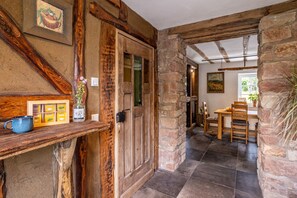 A rustic interior with exposed wooden beams, stone walls, a wooden door, and a dining area with a table and chairs. - Historic Farmhouse I Chimney I Terrace I Kitchen (Hillesheim)