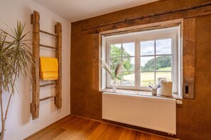 A room with a wooden ladder, a window with a view of greenery, and a radiator. - Historic Farmhouse I Chimney I Terrace I Kitchen (Hillesheim)