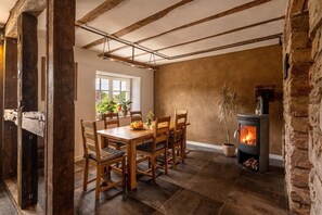 A rustic dining area with a wooden table, chairs, and a stone fireplace. - Historic Farmhouse I Chimney I Terrace I Kitchen (Hillesheim)