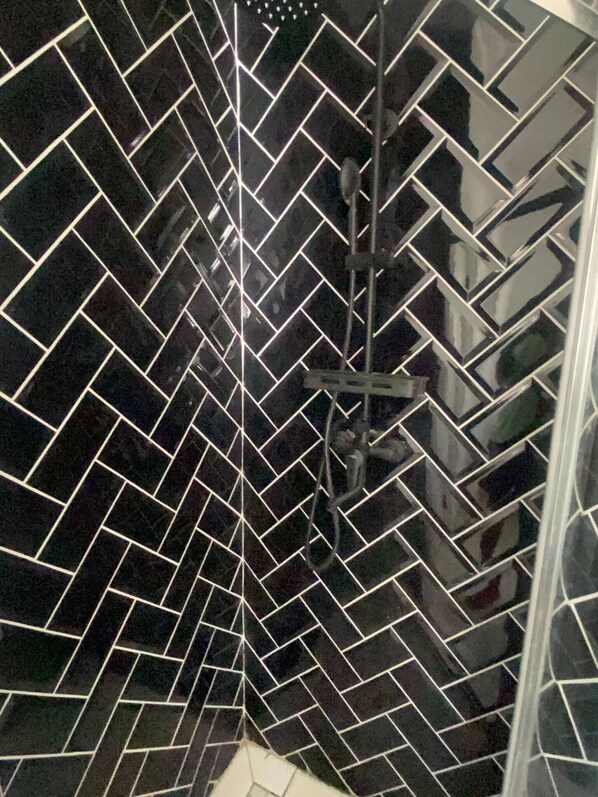 A shower area with black tiled walls and a visible showerhead.