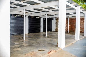 Un espace intérieur doté d’un sol en béton, de piliers blancs et de volets noirs fermés.