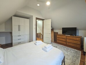 A bedroom with a bed, a television, a dresser, and a wardrobe.