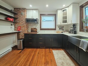 A kitchen with wooden flooring, a brick wall, and a window with a view.