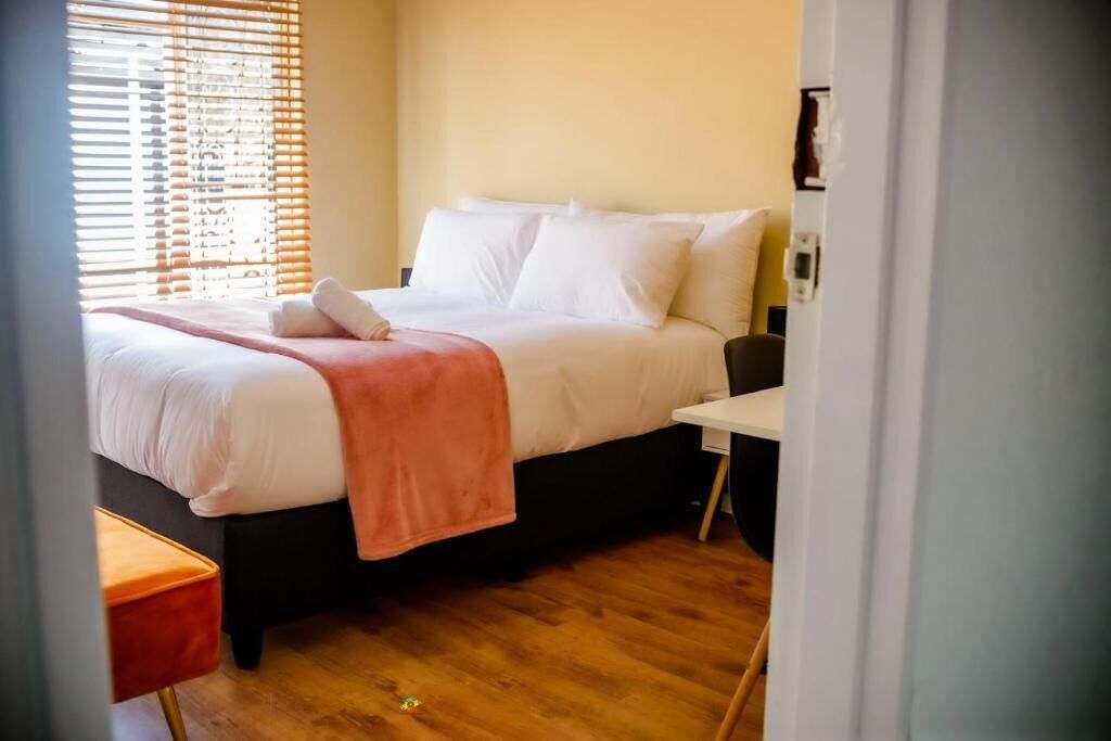 Ein Schlafzimmer mit einem Bett, einem Nachttisch und einem Fenster mit Jalousien.