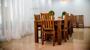 Uma área de refeições com cadeiras de madeira, uma mesa e um vaso de planta.
