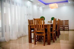 A dining area with wooden chairs, a table, and a potted plant.