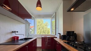 A kitchen with a window, a red cabinet, a sink, and a stove. - Les Toits de Bayonne - Mountain view (BAYONNE)
