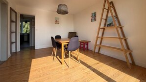 A room with a wooden floor, a dining table with chairs, a hanging light fixture, a ladder, and a small red stool. - Les Toits de Bayonne - Mountain view (BAYONNE)