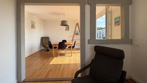 An open-plan living space with a dining area, a black chair, and a view through a window. - Les Toits de Bayonne - Mountain view (BAYONNE)