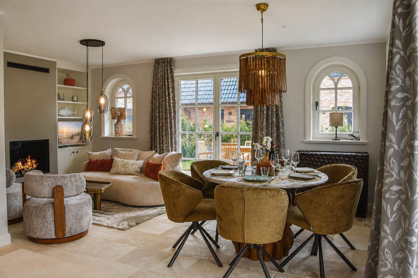 A dining area with a round table, wicker chairs, and a chandelier.