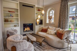 Ein Wohnzimmer mit Kamin, Sofa, Sesseln und Couchtisch.