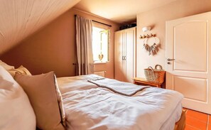 Ein Schlafzimmer mit Bett, einem Vorhangfenster, einer Tür und einer Wandleuchte.