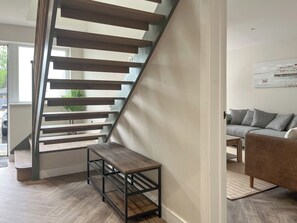 A modern staircase with wooden steps and metal railings, leading to a living area with a sofa and a coffee table. - Barncroft Retreat - UK51693 (High Seaton, near Workington)