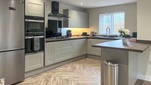 A modern kitchen with stainless steel appliances, a built-in oven, and a large window. - Barncroft Retreat - UK51693 (High Seaton, near Workington)