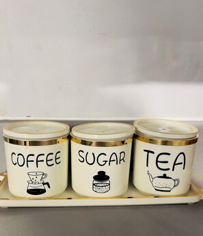Three white containers with gold trim labeled 'COFFEE,' 'SUGAR,' and 'TEA' with corresponding illustrations. - Deluxe Room in a 2Bedroom Aprt W Fast WiFi, Netflix, behind train station (West Midlands)