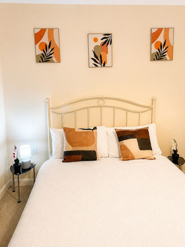 A neatly made bed with a white comforter and brown pillows, a white metal headboard, and three abstract art pieces on the wall. - Deluxe Private Room in a flat W Fast WiFi, Netflix, Free Parking (West Midlands)