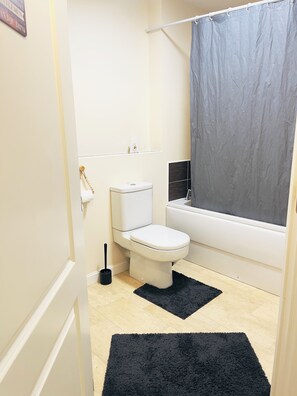 A bathroom with a toilet, a bathtub, a shower curtain, and a black rug. - Deluxe Private Room in a flat W Fast WiFi, Netflix, Free Parking (West Midlands)