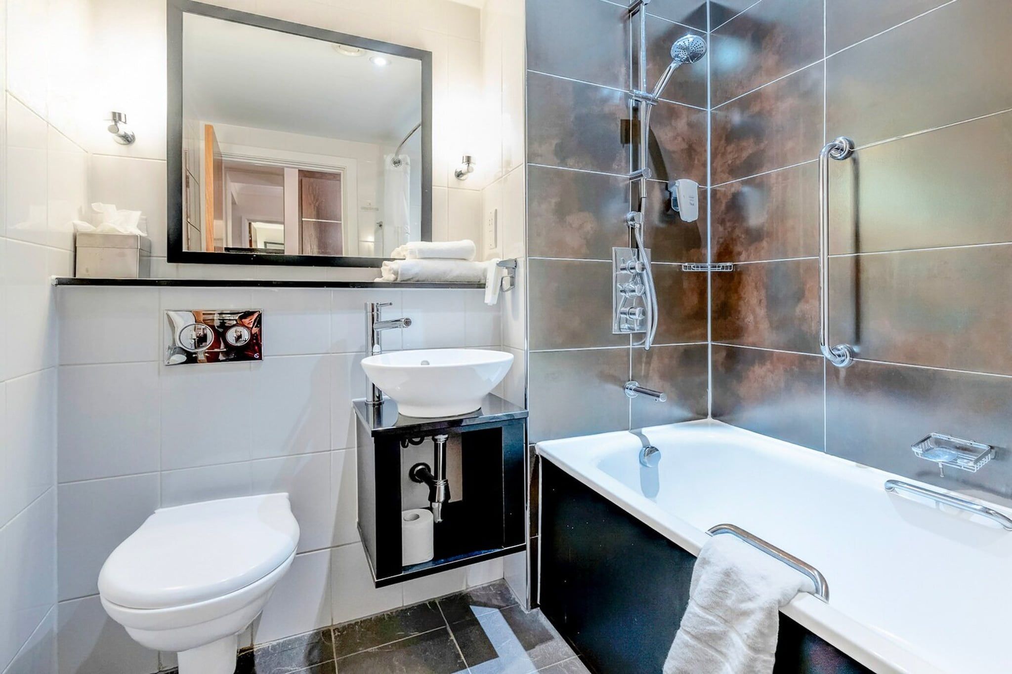 A modern bathroom with a toilet, sink, and bathtub.