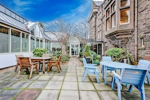 A courtyard with a table and chairs, a greenhouse, and stone buildings. - Landmark Hotel & SPA Leisure -Twin Room (Dundee)