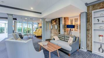 Eine moderne Hotellobby mit grauem Sofa, einem Holztisch und einer Wand aus Stein.