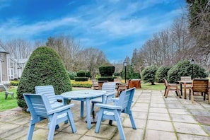 A patio with blue chairs and tables, surrounded by neatly trimmed hedges and trees. - Landmark Hotel & SPA Leisure -Twin Room (Dundee)