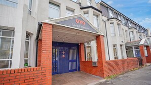 A building with a blue entrance, a sign reading 'OYO Cardiff Central,' and a brick facade. - Standard Triple Room (Cardiff)