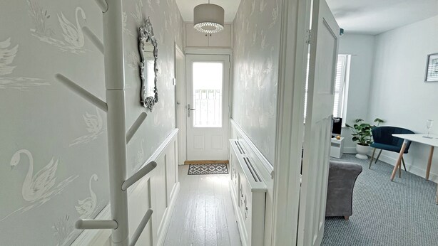 A hallway with white walls and a door at the end. - 1 bedroom accommodation in Ely (Ely)