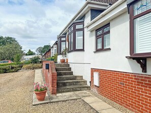 A residential house with a brick exterior, white walls, and a set of concrete steps leading to a door. - 1 bedroom accommodation in Ely (Ely)