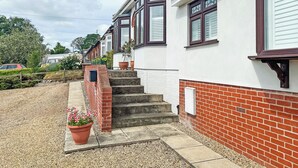 A residential house with a brick exterior, white walls, and a set of concrete steps leading to a door. - 1 bedroom accommodation in Ely (Ely)