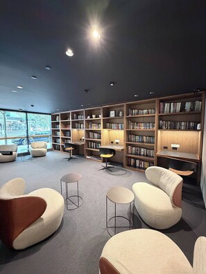 Et moderne bibliotek med reoler, behagelige siddepladser og udsigt gennem store vinduer.
