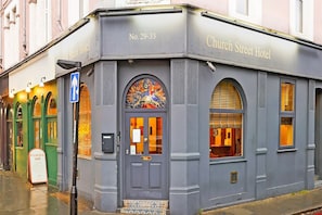 A corner building with a sign reading 'Church Street Hotel' and a door with a window above it. - Standard Single Room - Shared (London)