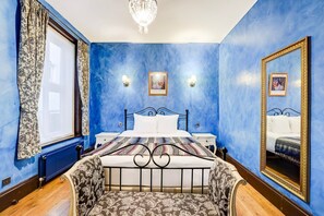 A bedroom with a bed, bedside tables, a mirror, and a chandelier. - Standard Single Room - Shared (London)