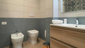 A modern bathroom with a bidet, toilet, vanity with a mirror, and a trash bin. - Elegant Suite between Sorrento and the Amalfi Coast (Castellammare di Stabia)