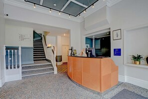 A reception area with a reception desk, a staircase, and a wall-mounted sign. - Sunday London Staines-upon-Thames Heathrow T8 - Standard Family of 3 Room (London)