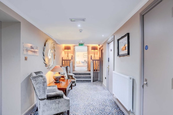 A hallway with a dining area featuring a table and chairs, a radiator, and a framed picture on the wall.