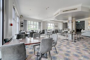 A spacious conference room with multiple tables and chairs, large windows, and a patterned carpet. - Sunday London Staines-upon-Thames Heathrow T8 - Standard Family of 3 Room (London)