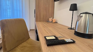 A modern hotel room with a wooden desk, a sofa, a flat-screen TV, a coffee maker, and a remote control. - Suite with balcony near Pompeii, Sorrento, and Amalfi (Castellammare di Stabia)