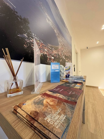 A reception desk with a large poster, a glass bottle with reed sticks, and a blue informational sign.. Suite with balcony near Pompeii, Sorrento, and Amalfi