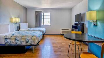A hotel room with two beds, a dining table, a TV, and a window.